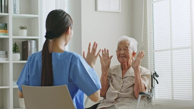 Young Asian woman nurse, caregiver assist a senior Asian woman to do physical therapy and exercise at home