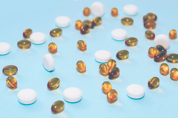 Fish oil pills in golden jelly shell and vitamins on paper background.
