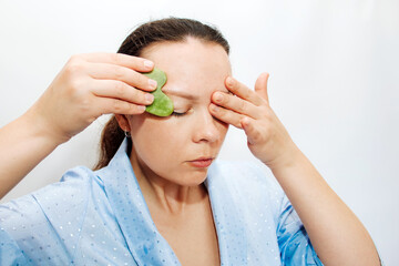 The girl makes a massage with a jade massager close-up, problem skin.