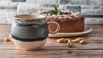a large earthenware mug for tea in the foreground, blurred pie counters in the background, nuts on the table