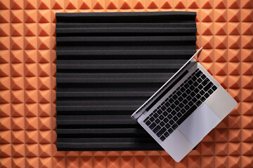 Computer laptop on acoustic foam background texture. Music concept in studio