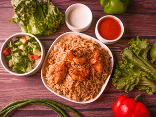 chicken tikka biryani in a dish served with salad, raita, sauce and drink top view of indian and pakistani biryani deal