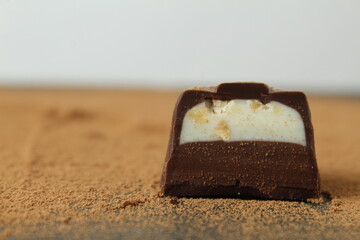 body chocolate candy with chocolate and white milk cream filling close-up against the cocoa background. A day of chocolate sweets without diet. handmade sweets