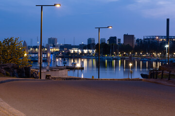 View of a shore promenade with calm sea and sleeping city in the background.