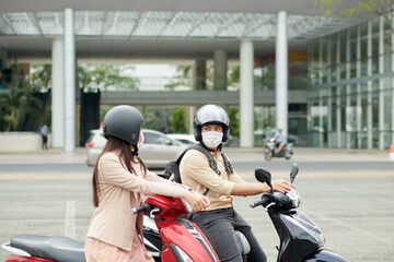 Fototapeta na wymiar Business colleagues wearing protective helmets when riding on scooters to office in morning