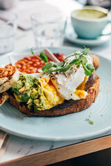 Healthy breakfast from poached eggs, grilled halloumi, Scrambled smoked harissa tofu, smashed avocado, grilled mushrooms and tomato beans on toast
