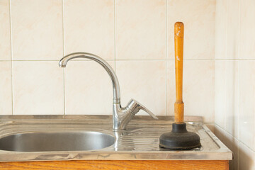 The plunger stands at the sink in the kitchen, cleaning clogged pipes, plunger for cleaning pipes