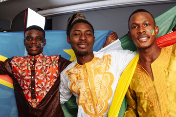 Concept of friendship and peace between countries: African man and two Latin ladies in national clothes show hug together with body arts flags Congo, Brazil, Ecuador