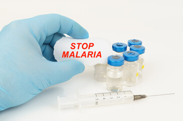 In his hand is a piece of paper with the inscription - STOP MALARIA, next to it lies a syringe and...