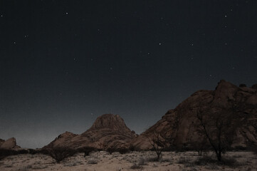 A starry night sky highlights the rocks of the namibian desert.
