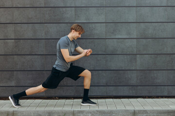 Young man doing stretching exercises against black wall