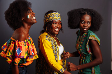 Three young beautiful African fashion models have fun and laughing in traditional dress. Women from the Congo Republic, Ivory Coast, and Zimbabwe