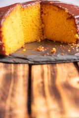 Sliced ​​carrot cake, covered in chocolate on stone surface over rustic wood, selective focus.