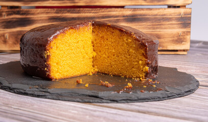 Sliced ​​carrot cake, covered in chocolate on stone surface over rustic wood, selective focus.