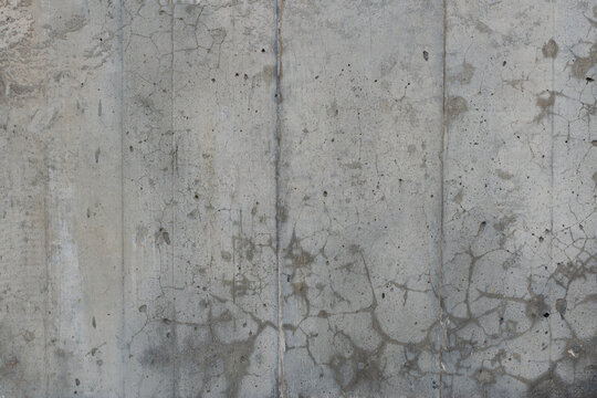 Reinforced concrete texture with areas covered with small cracks and spots. Surface of old and dirty reinforced concrete with traces of wooden formwork, background, high resolution.