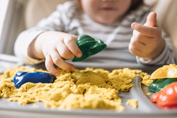 Cute little boy playing with kinetic sand. Development of fine motor skills. Early sensory...