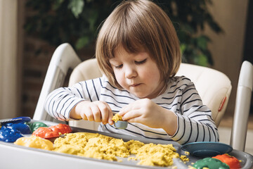Cute little boy playing with kinetic sand. Development of fine motor skills. Early sensory...