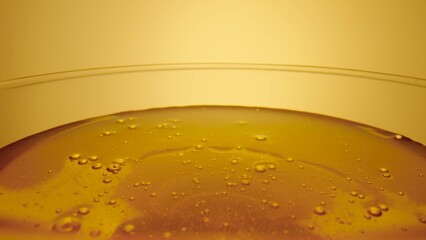 Thick golden honey flowing into a glass. A jet of fresh organic honey molasses pours close up. Sweet product of beekeeping. Healthy dessert, sweet food, natural syrup spilled.