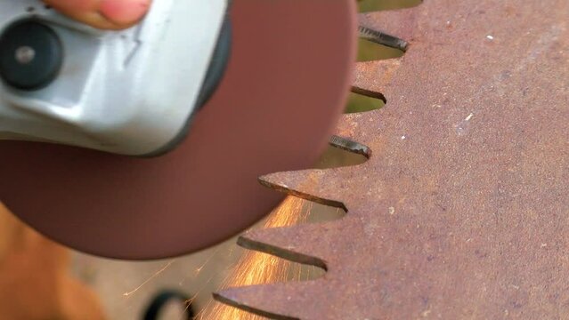 Old rusty hand saws are sharpened. Sparks fly from the saw