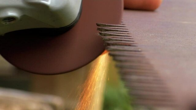 Old rusty hand saws are sharpened. Sparks fly from the saw