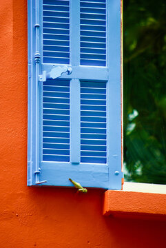 Orange colored stone building with blue painted wooden window shutter in Provence in France.
