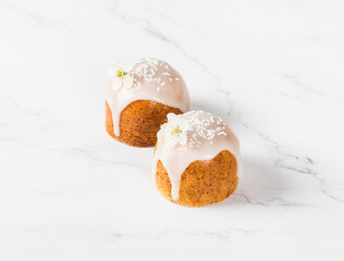 Two Cakes with white sugar glaze, decorated with a flower and confectionery sprinkles. Light background