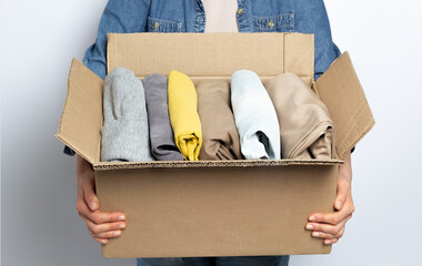 A woman is holding a box with donation or charity clothes in her hands.