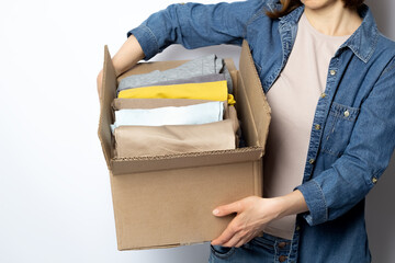 A woman is holding a box with donation or charity clothes in her hands.