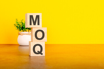 moq - text on wood cubes stack, yellow background