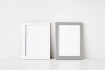 Two empty picture frames are placed on the white table by the wall. Copy space