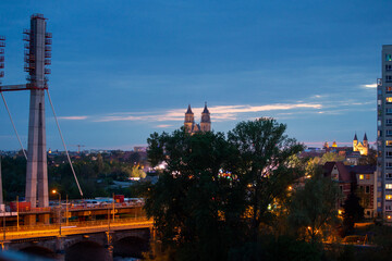 Panorama und Skyline von Magdeburg, Sachsen-Anhalt, Landeshauptstadt am Fluss Elbe, mit Hochhäusern, Johanniskirche, neuer Brücke über der Elbe mit Beleuchtung und Plattenbauten
