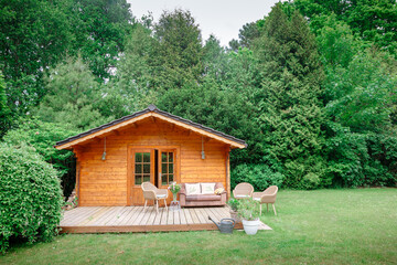 Leather sofa on a terrace outside next to a wooden house. Wooden garden house with outdoor seating....