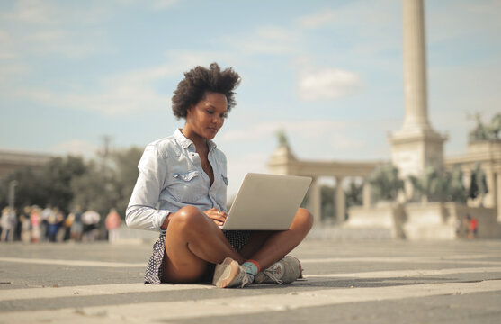 young woman sitting in the street uses a computer