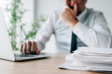 Choosing the best candidate, employer with job applications and cv papers piled on office desk