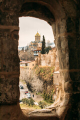 Tbilisi, Georgia. Scenic View Famous Landmark Sameba Church through ancient Metekhi church arch,...