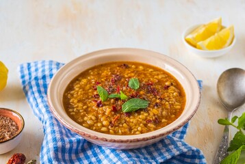 Red lentil and bulgur bride soup in a clay bowl on a light concrete background. Turkish cuisine. Recipes lentils, legumes