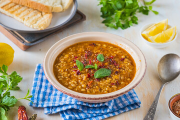 Red lentil and bulgur bride soup in a clay bowl on a light concrete background. Turkish cuisine....