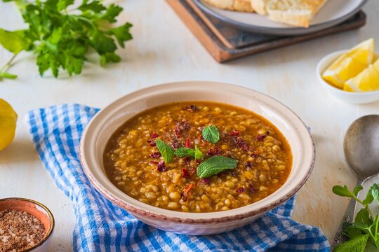 Red lentil and bulgur bride soup in a clay bowl on a light concrete background. Turkish cuisine. Recipes lentils, legumes