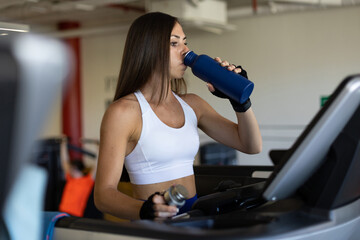 woman drinking water after training