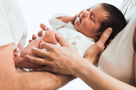 Crop Mom And Dad Hugging Infant Against White Background