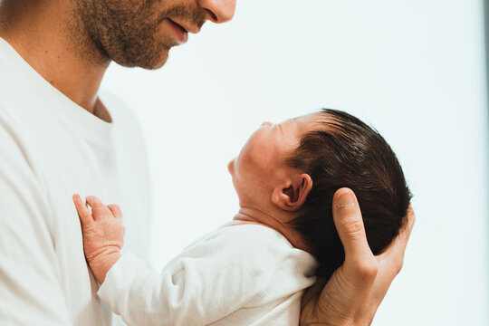 Crop unrecognizable father holding cute baby against white background