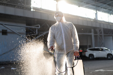 Man dressed white protective overalls spraying surface antibacterial sanitizer sprayer during quarantine