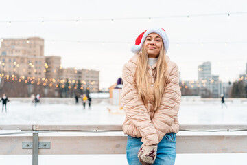 Outdoor portrait young beautiful fashionable woman wearing Santa hat, posing street of European city. Winter Christmas holidays concept.