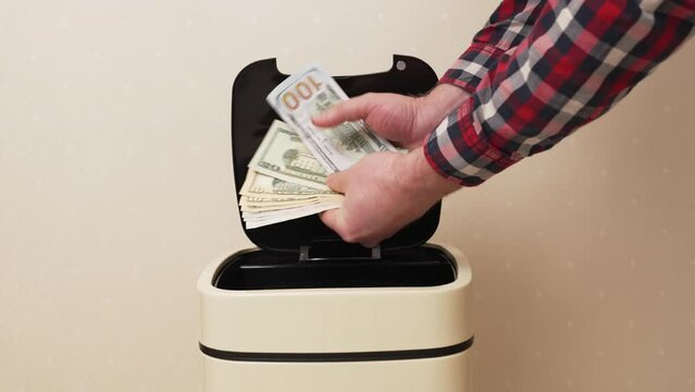 hand opens and throws american money into Sensory trash can. concept of inflation