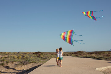 Happy little brother launching colorful kites in countryside