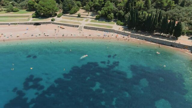 Montenegro. Adriatic Sea. Milocer beach. Summer. Sunny weather. High season. A very popular tourist spot. Drone. Flight. The camera moves from right to left