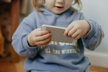 Little girl in violet hoodie using a phone on white background 