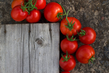 fresh red ripe tomatoes near the empty wooden grey board