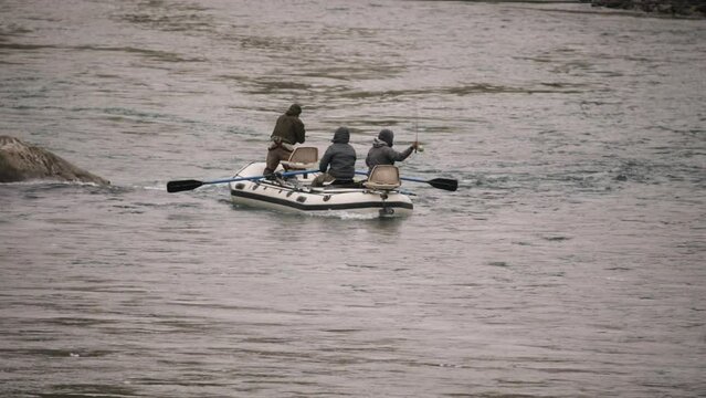 Sports and recreation. People fly fishing from an inflatable boat in the river. The men fish and row along the current. 
