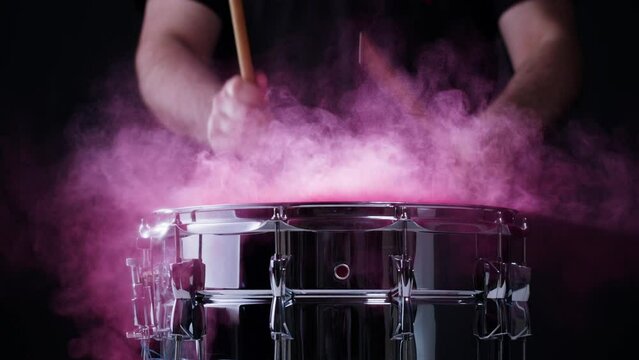  Playing drums with colorful pink powder close-up. Drummer playing musical instrument, professional musician player. 